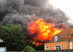 Parcelhus der er i brand. Store synlige flammer og sort røg stiger op fra taget.